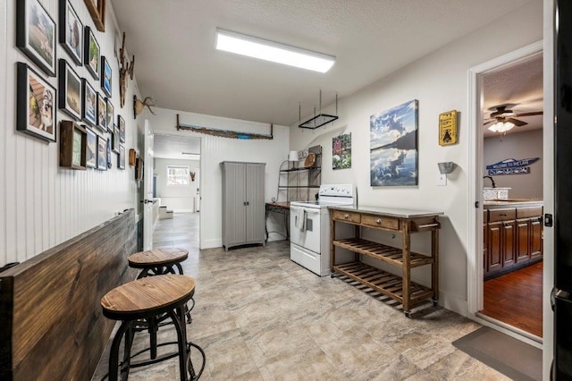 kitchen featuring a kitchen bar, white electric range, and ceiling fan