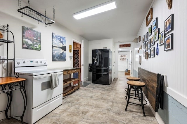 kitchen with electric stove and black fridge with ice dispenser