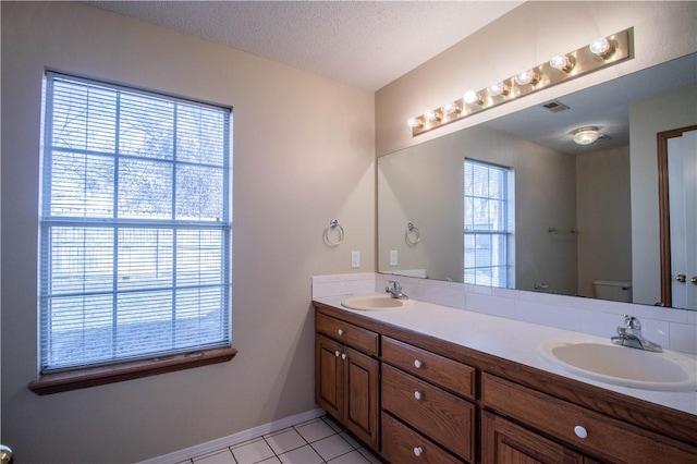 bathroom featuring vanity, toilet, a textured ceiling, and a wealth of natural light