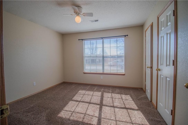 carpeted empty room featuring ceiling fan and a textured ceiling