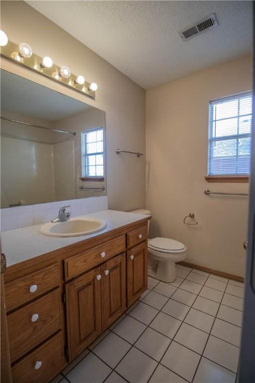 bathroom featuring vanity, walk in shower, toilet, tile patterned floors, and a textured ceiling