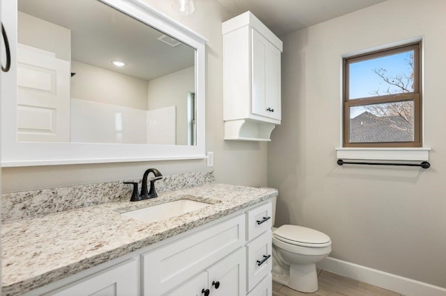 bathroom featuring visible vents, baseboards, toilet, wood finished floors, and vanity