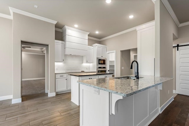 kitchen with a barn door, a sink, a peninsula, and light wood finished floors