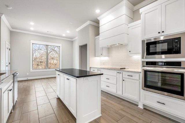 kitchen with white cabinets, ornamental molding, stainless steel appliances, a kitchen island, and tasteful backsplash