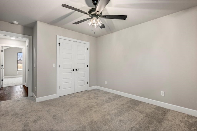 unfurnished bedroom with baseboards, carpet floors, ceiling fan, and a closet