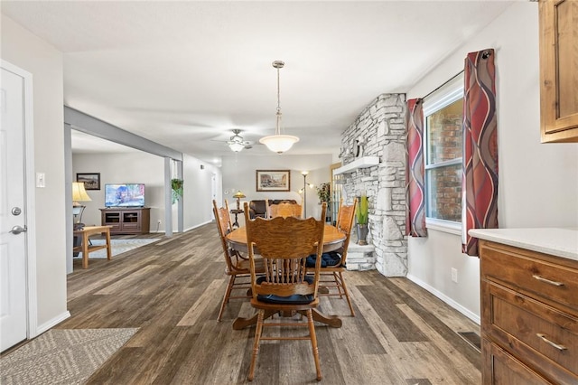 dining room with a stone fireplace and dark hardwood / wood-style flooring