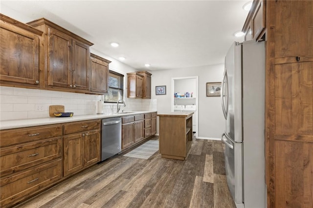 kitchen with sink, tasteful backsplash, appliances with stainless steel finishes, dark hardwood / wood-style floors, and a kitchen island