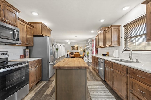 kitchen featuring a kitchen island, appliances with stainless steel finishes, pendant lighting, sink, and wooden counters