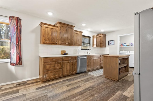 kitchen with sink, dishwasher, backsplash, dark hardwood / wood-style floors, and separate washer and dryer