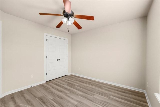 unfurnished bedroom featuring ceiling fan, light wood-type flooring, and a closet