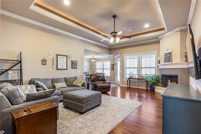 living room featuring ornamental molding, dark hardwood / wood-style flooring, and a tray ceiling