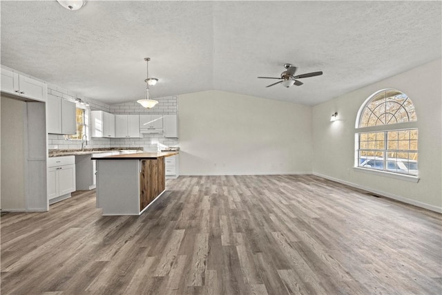 kitchen featuring white cabinetry, hanging light fixtures, a kitchen island, and hardwood / wood-style flooring