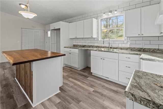 kitchen with white cabinets, a center island, sink, and wooden counters