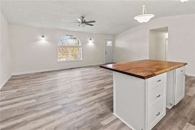 kitchen featuring light hardwood / wood-style flooring, butcher block counters, hanging light fixtures, white cabinetry, and a kitchen island