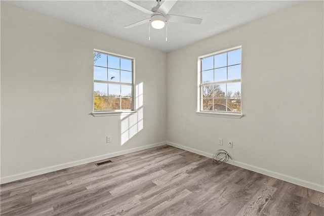 spare room featuring ceiling fan, a healthy amount of sunlight, and light hardwood / wood-style flooring