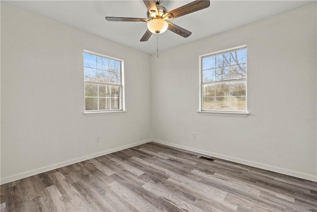 spare room with ceiling fan, a healthy amount of sunlight, and light wood-type flooring