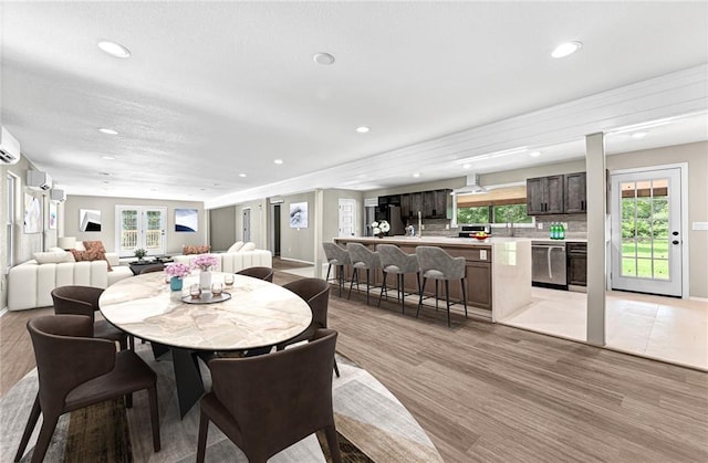 dining area featuring a healthy amount of sunlight, light hardwood / wood-style floors, and a wall mounted air conditioner