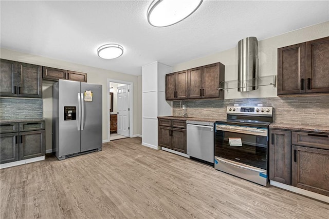 kitchen with stainless steel appliances, light hardwood / wood-style floors, dark brown cabinets, and wall chimney range hood