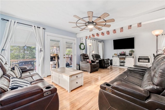 living room featuring light hardwood / wood-style flooring, heating unit, ceiling fan, and french doors