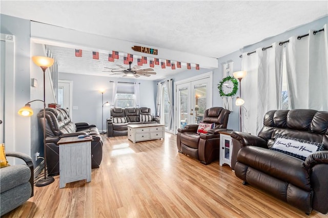 living room featuring french doors, a textured ceiling, and light wood-type flooring