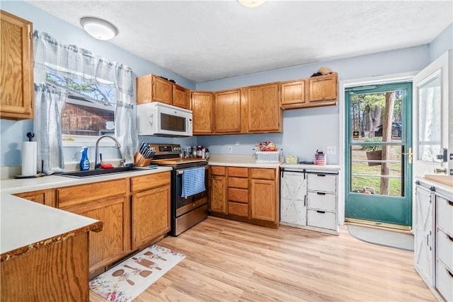 kitchen featuring electric stove, sink, a textured ceiling, and light wood-type flooring