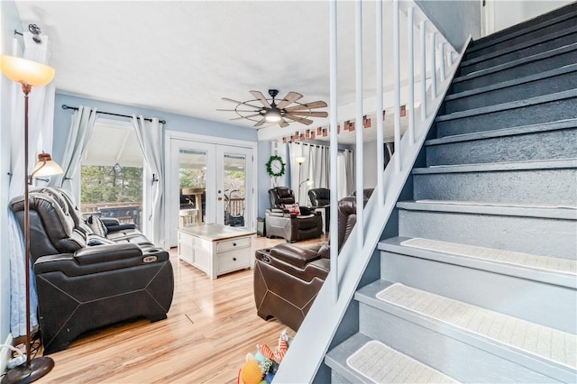 living room featuring french doors, ceiling fan, and light wood-type flooring