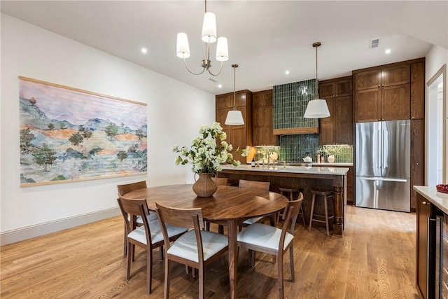 dining space featuring a notable chandelier and light wood-type flooring