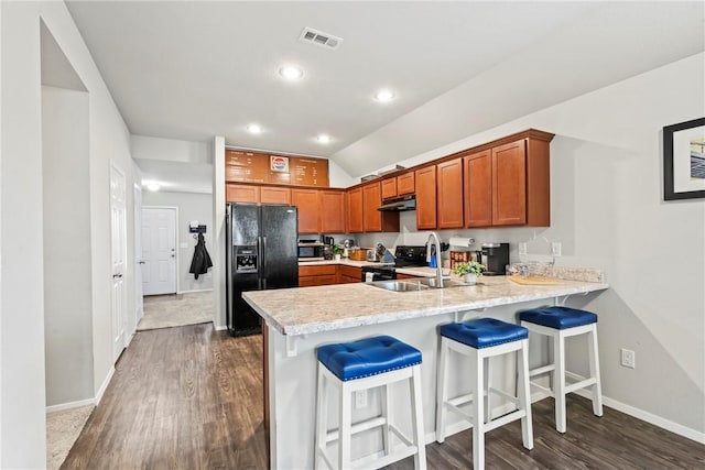 kitchen featuring a breakfast bar, sink, vaulted ceiling, dark hardwood / wood-style floors, and black appliances