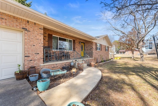 doorway to property featuring a garage, a yard, and covered porch