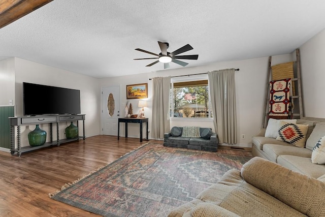 living room with ceiling fan, wood-type flooring, and a textured ceiling