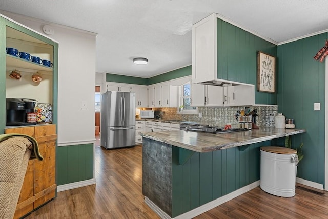 kitchen with white cabinetry, dark wood-type flooring, stainless steel refrigerator, and kitchen peninsula