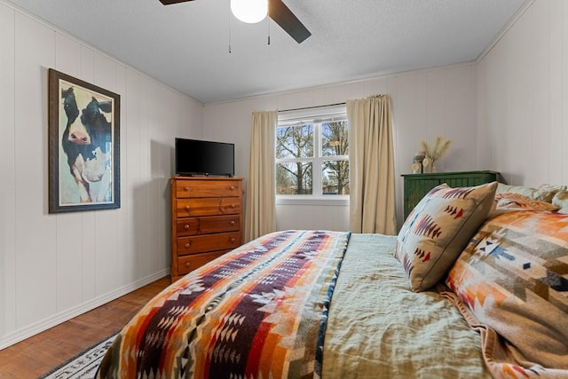 bedroom featuring ceiling fan, wood-type flooring, and a textured ceiling