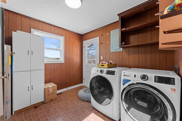 washroom with cabinets, independent washer and dryer, a textured ceiling, and wood walls