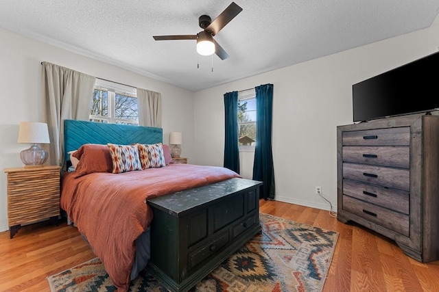 bedroom with ceiling fan, light hardwood / wood-style flooring, and a textured ceiling