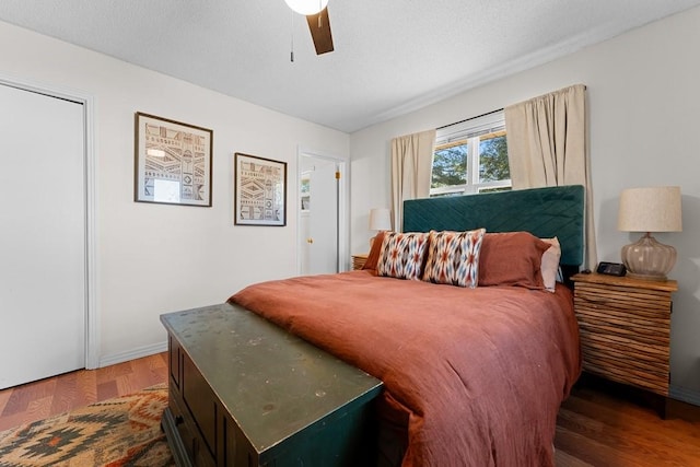 bedroom with dark wood-type flooring, ceiling fan, and a textured ceiling