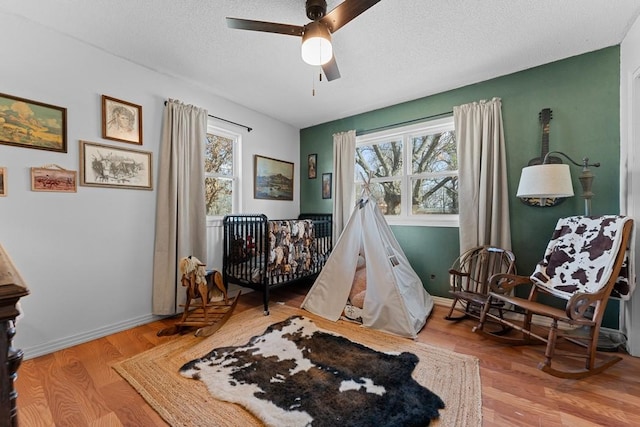 sitting room featuring ceiling fan, a textured ceiling, light hardwood / wood-style floors, and a healthy amount of sunlight