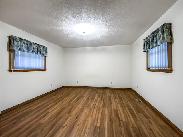 empty room featuring a healthy amount of sunlight, hardwood / wood-style floors, and a textured ceiling