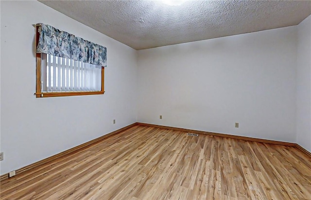 spare room featuring a textured ceiling and light wood-type flooring