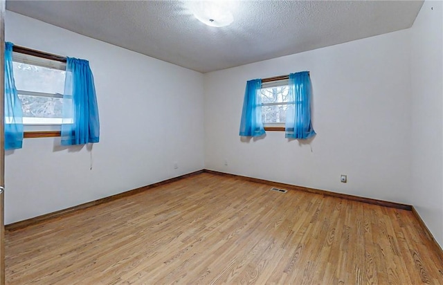 spare room featuring light hardwood / wood-style floors and a textured ceiling