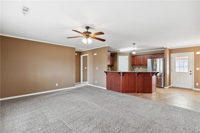 kitchen featuring pendant lighting, stainless steel refrigerator, a kitchen breakfast bar, light carpet, and kitchen peninsula