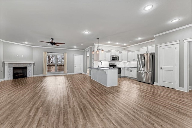 kitchen featuring pendant lighting, a breakfast bar area, white cabinets, a kitchen island with sink, and stainless steel appliances