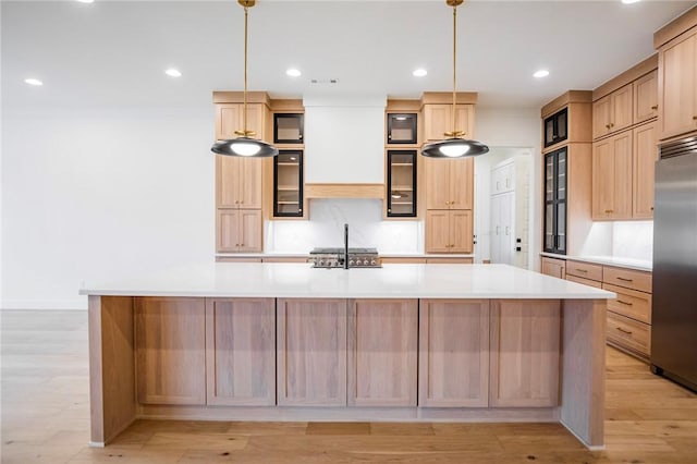 kitchen featuring light brown cabinetry, decorative light fixtures, a spacious island, and appliances with stainless steel finishes