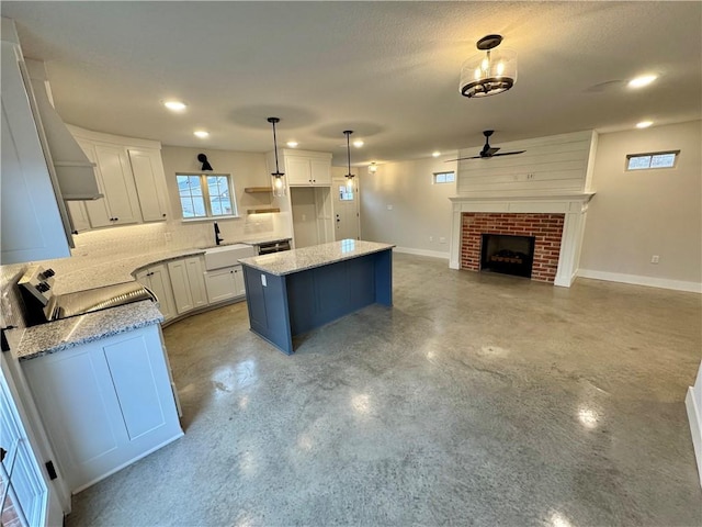 kitchen with a kitchen island, pendant lighting, a fireplace, white cabinets, and stove