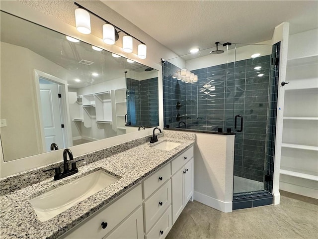 bathroom with vanity, a shower with door, and a textured ceiling