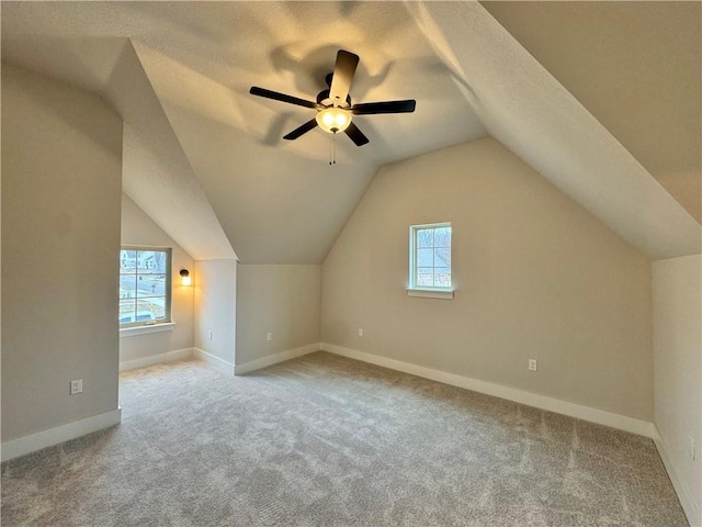 bonus room with ceiling fan, light colored carpet, vaulted ceiling, and a textured ceiling