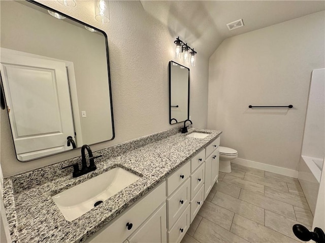 bathroom featuring a bathing tub, vanity, vaulted ceiling, and toilet