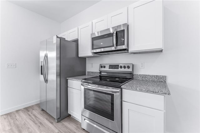 kitchen with appliances with stainless steel finishes, light stone countertops, light hardwood / wood-style floors, and white cabinets