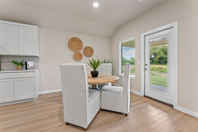 dining room with vaulted ceiling and light wood-type flooring