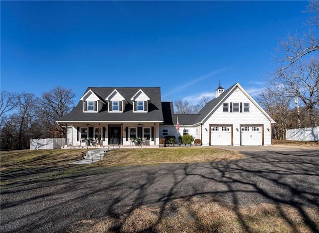 new england style home featuring a porch, a garage, and a front yard