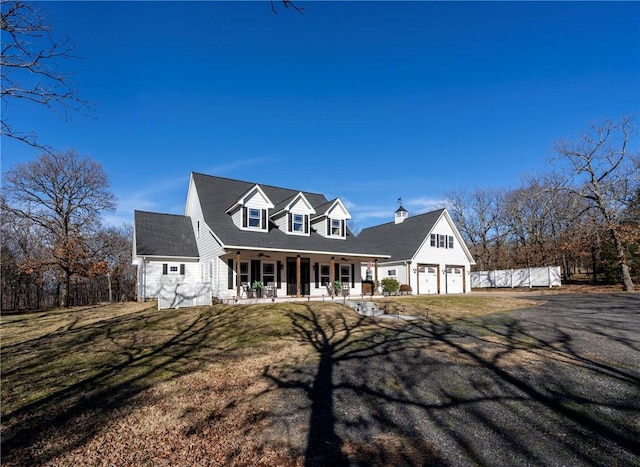 new england style home with a porch, a garage, and a front lawn